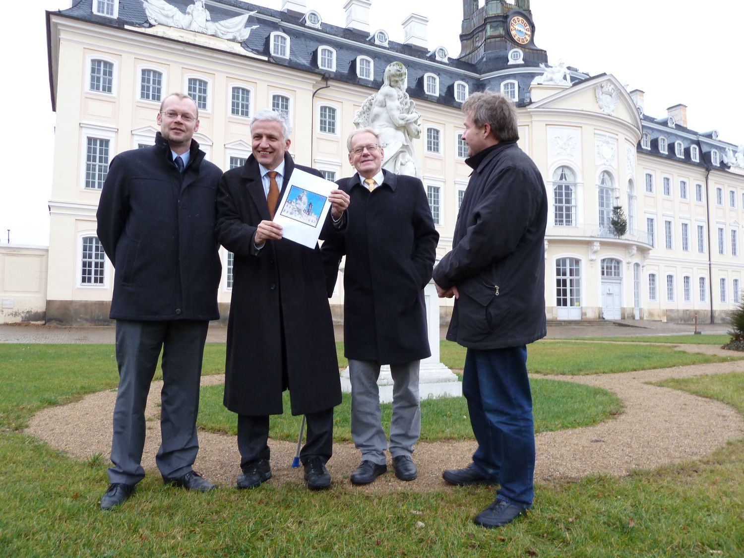 Manfred Kolbe (m.) bringt symbolhaft die Briefmarke nach Hubertusburg.